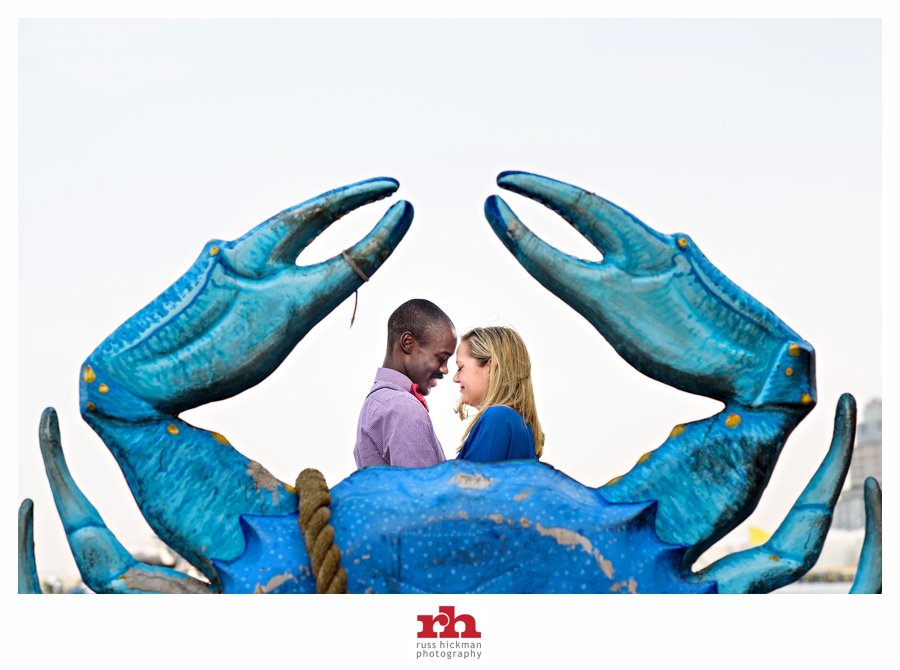 An Engaged Couple embrace behind a Baltimore crab in this Baltimore Engagement Session.